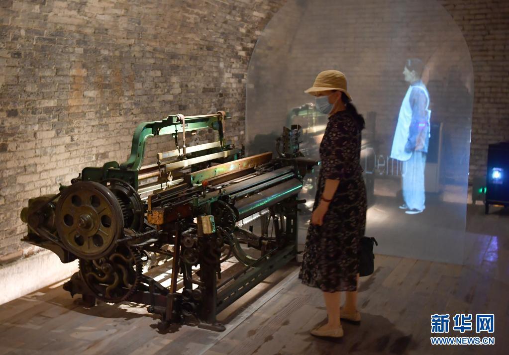 6月9日，游客在“窯洞工廠”內(nèi)參觀全息影像模擬的抗戰(zhàn)時(shí)期紡紗女工接線頭的場(chǎng)景。