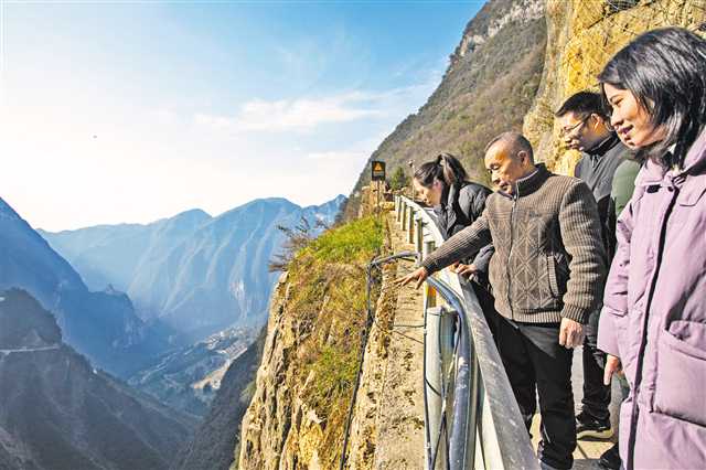 1月11日,巫山縣竹賢鄉(xiāng)下莊村“天路”上,毛相林(右三)給袁孝鑫(右一)等年輕人講述修路的往事。