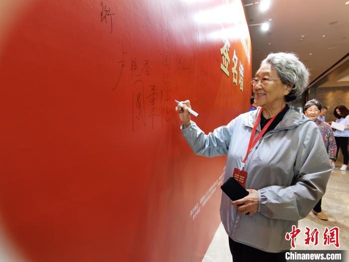 圖為中國新聞社原副社長周秉德簽字留念?!∑钤鲚?攝 圖為中國新聞社原副社長周秉德簽字留念?!∑钤鲚?攝